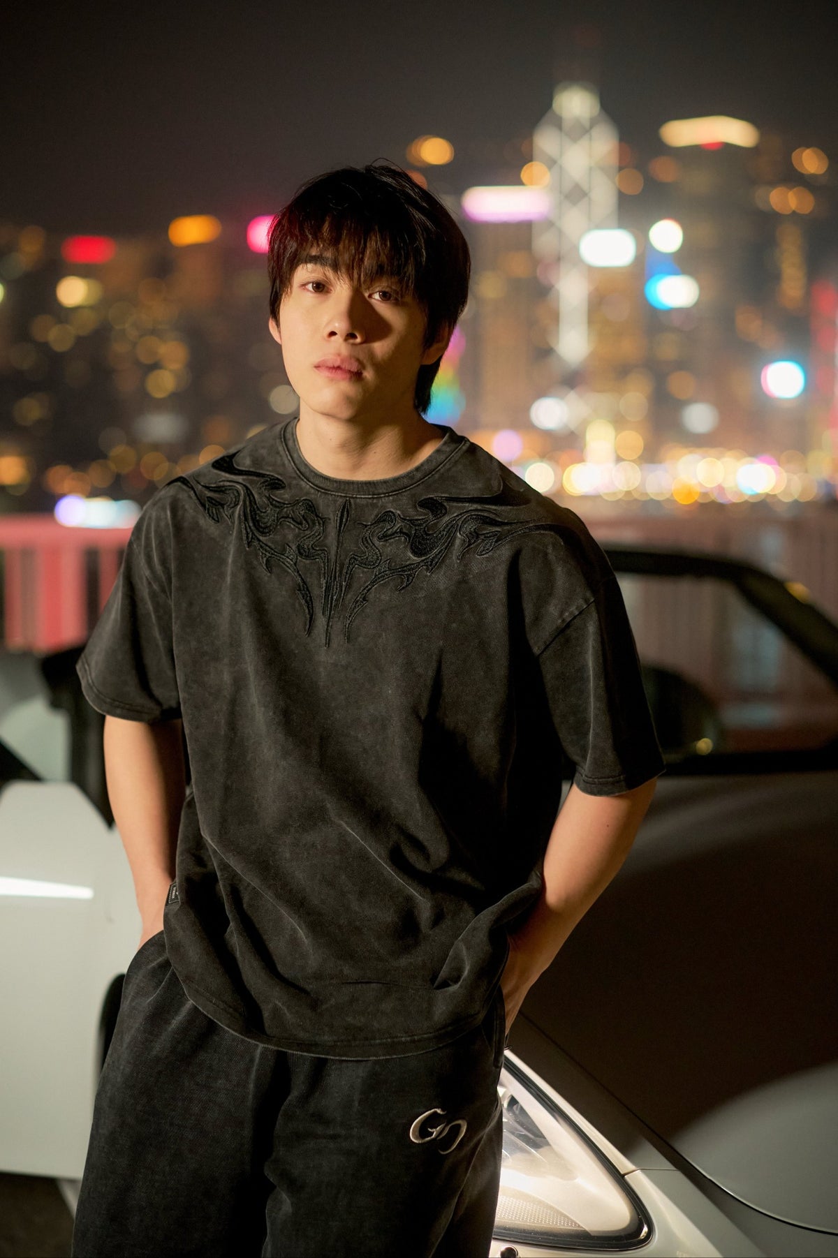DROP 01 — Washed Sigil Tee front view against the Hong Kong skyline at night.
